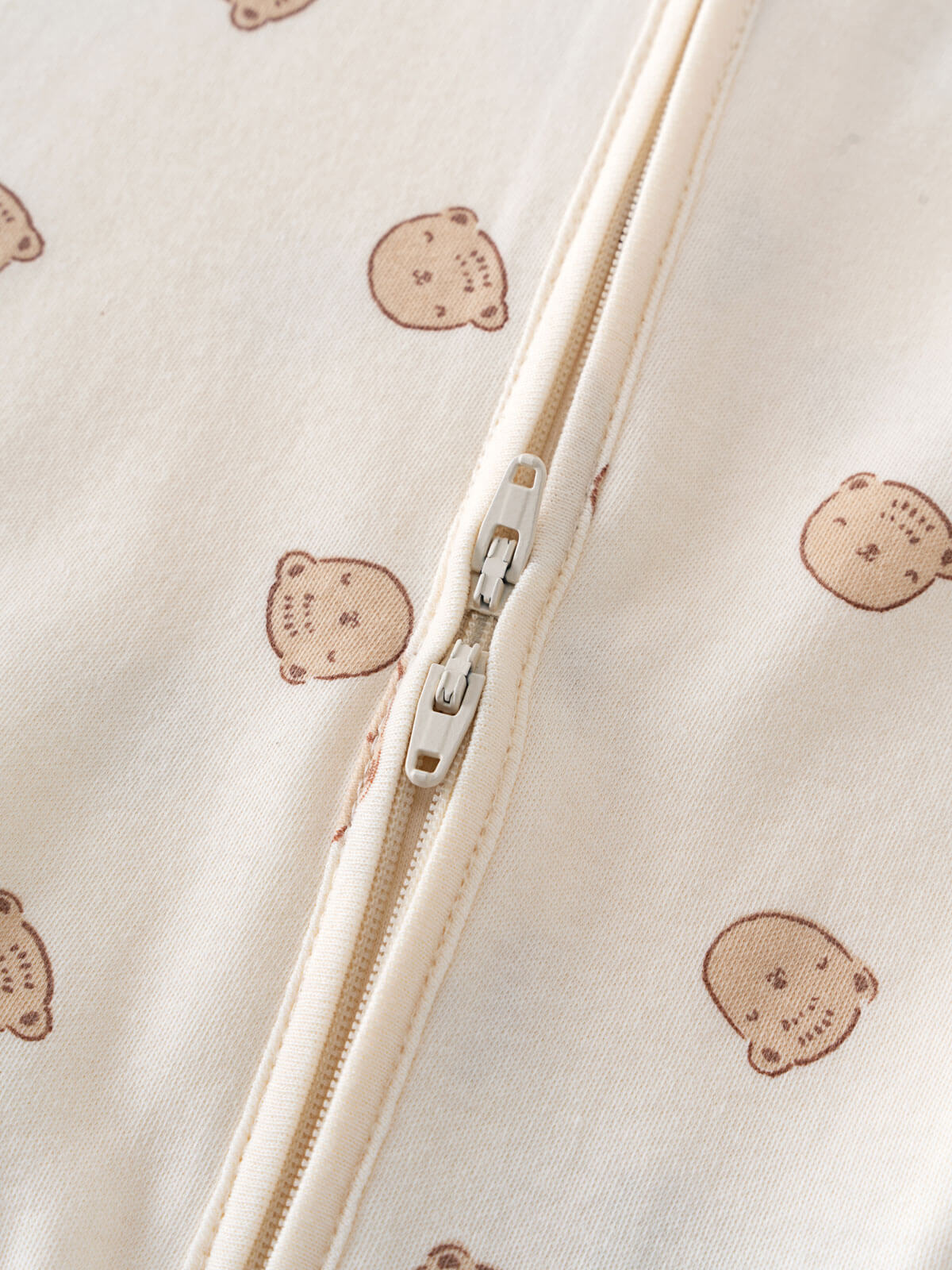 Close-up of cream fabric with bear print and white zipper detail Printed Long Sleeve One Piece - Cosy Bear Ecru Baby boy