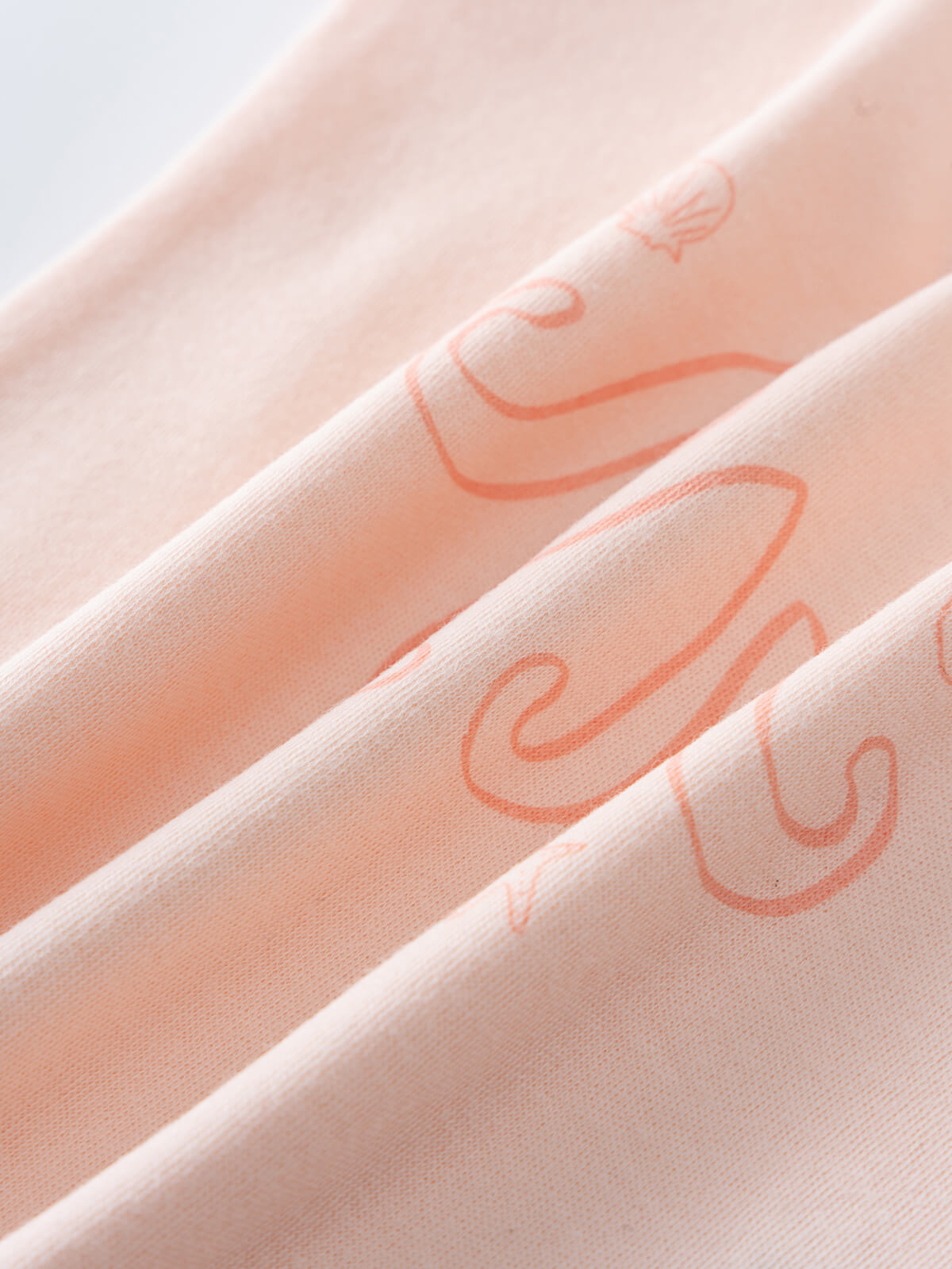Close-up of peach fabric with orange octopus print design Andi Sleeveless Tee - Octy Baby girl