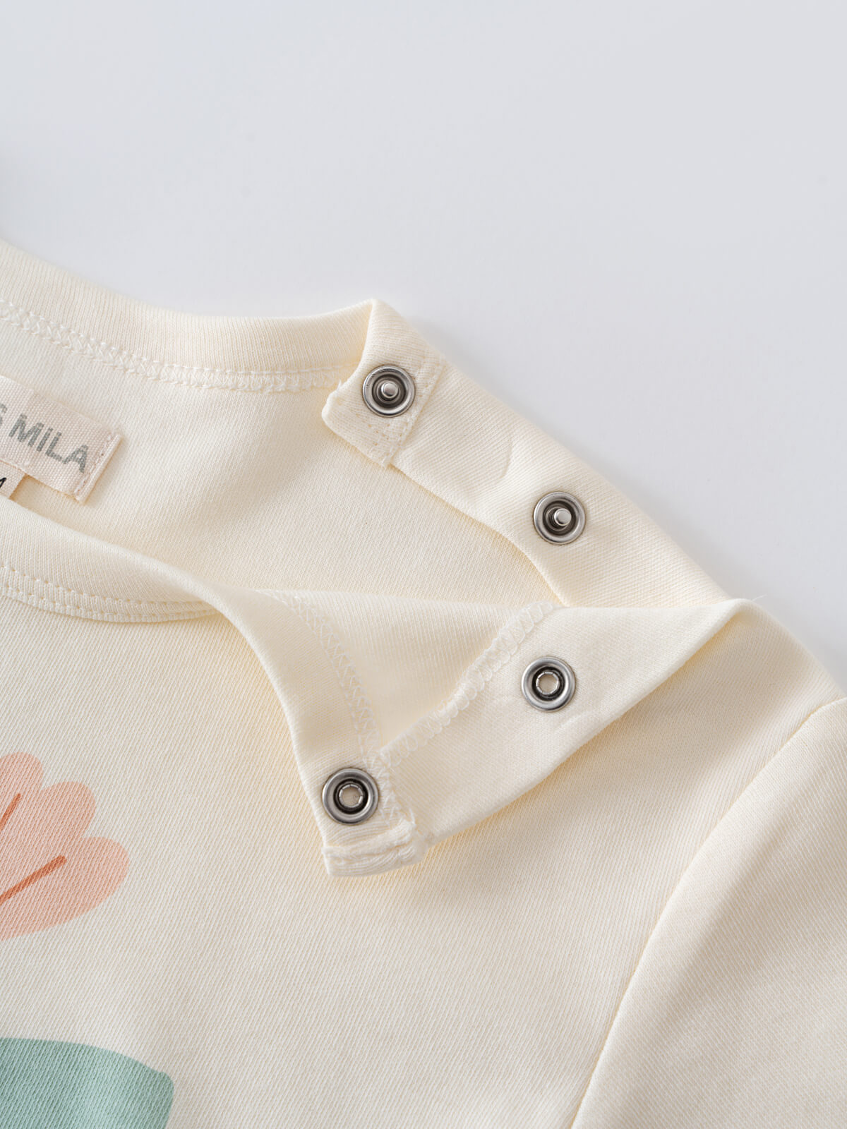 Close-up of cream-colored baby garment shoulder with metal snap buttons Angel Short Sleeve Tee - Angel Fish Baby girl