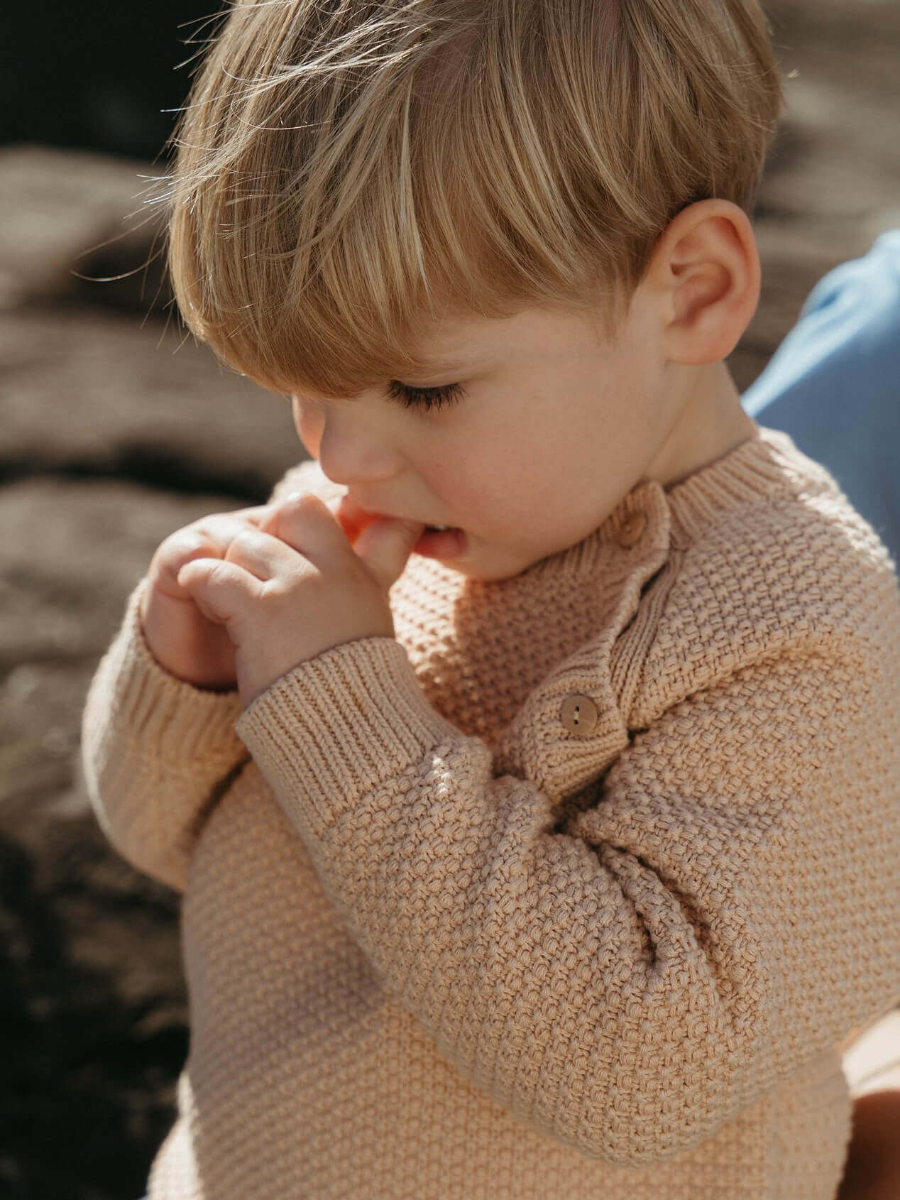 Child wearing a beige knitted sweater outdoors
