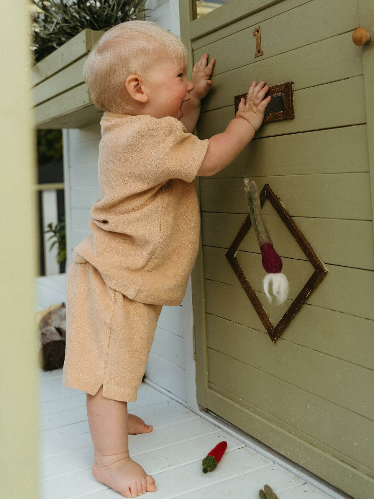 Child playing with a wooden playhouse door