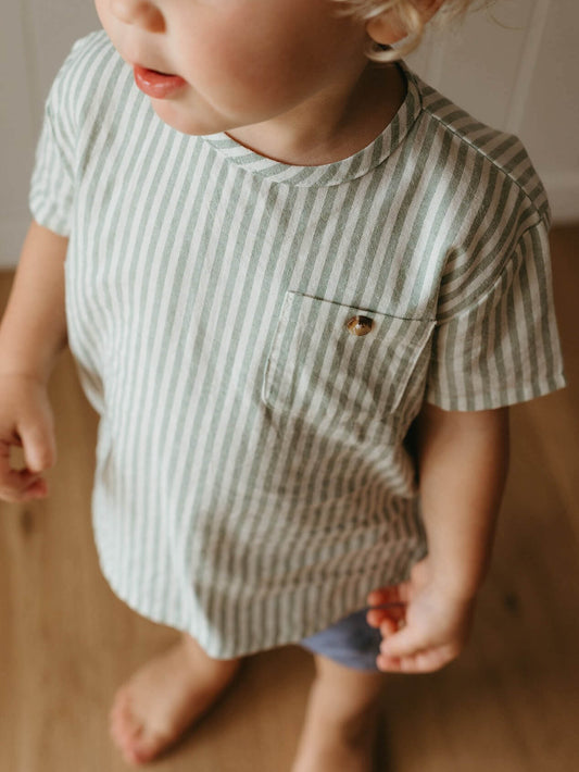 Child wearing a striped shirt with a pocket on a neutral background