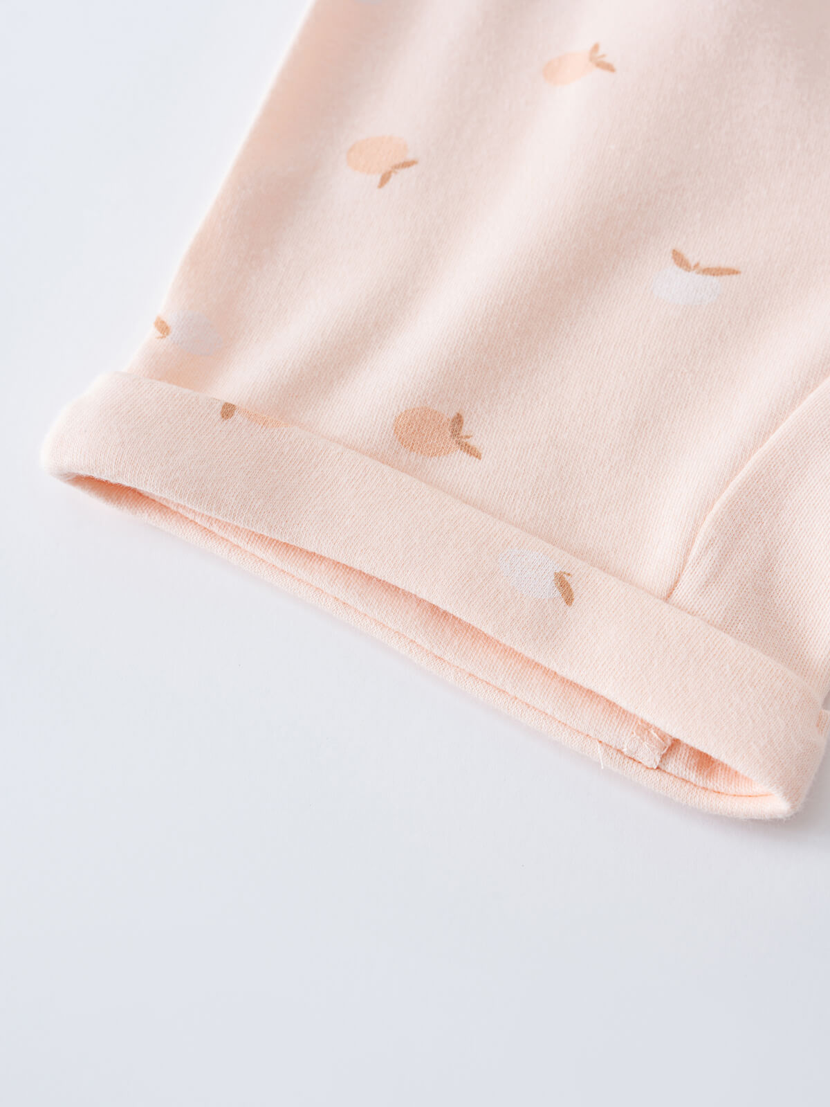 Close-up of pale pink fabric cuff with small peach-colored apple print Gemma Shorts - Apples Baby girl