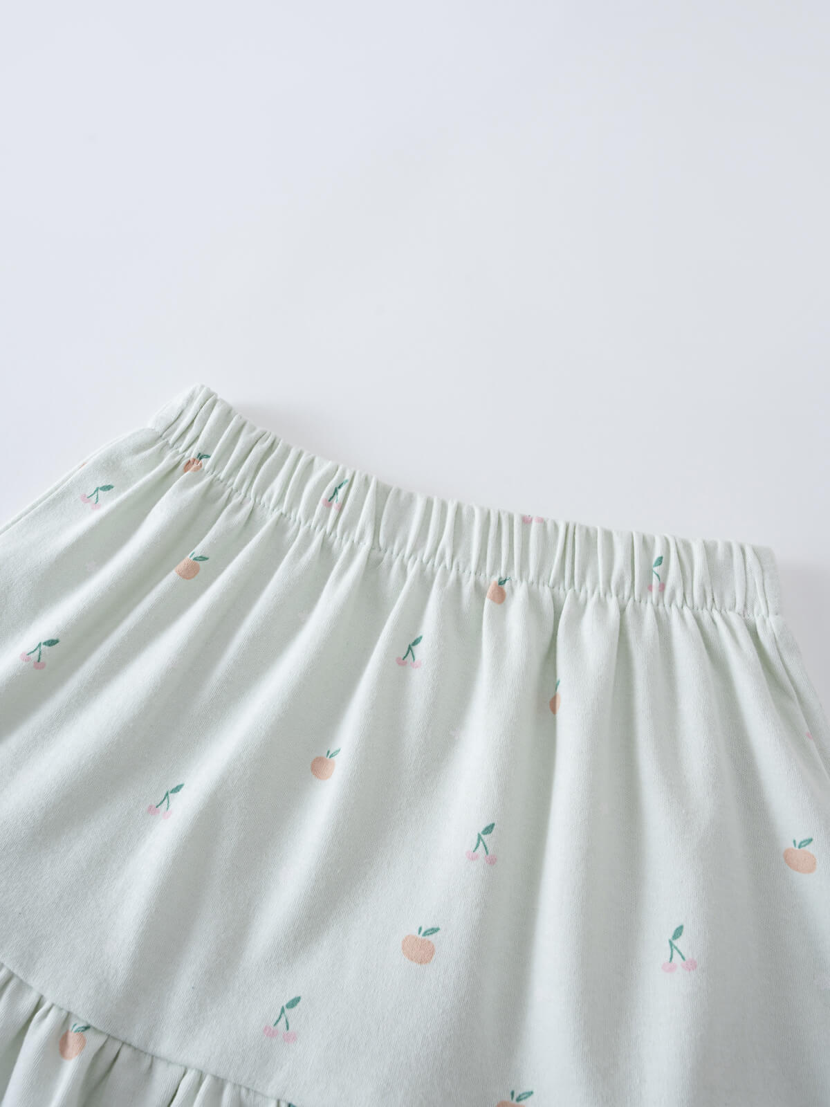 Close-up of a light green skirt with small peach and cherry embroidery Jersey Skirt - Summer Fruits Girls