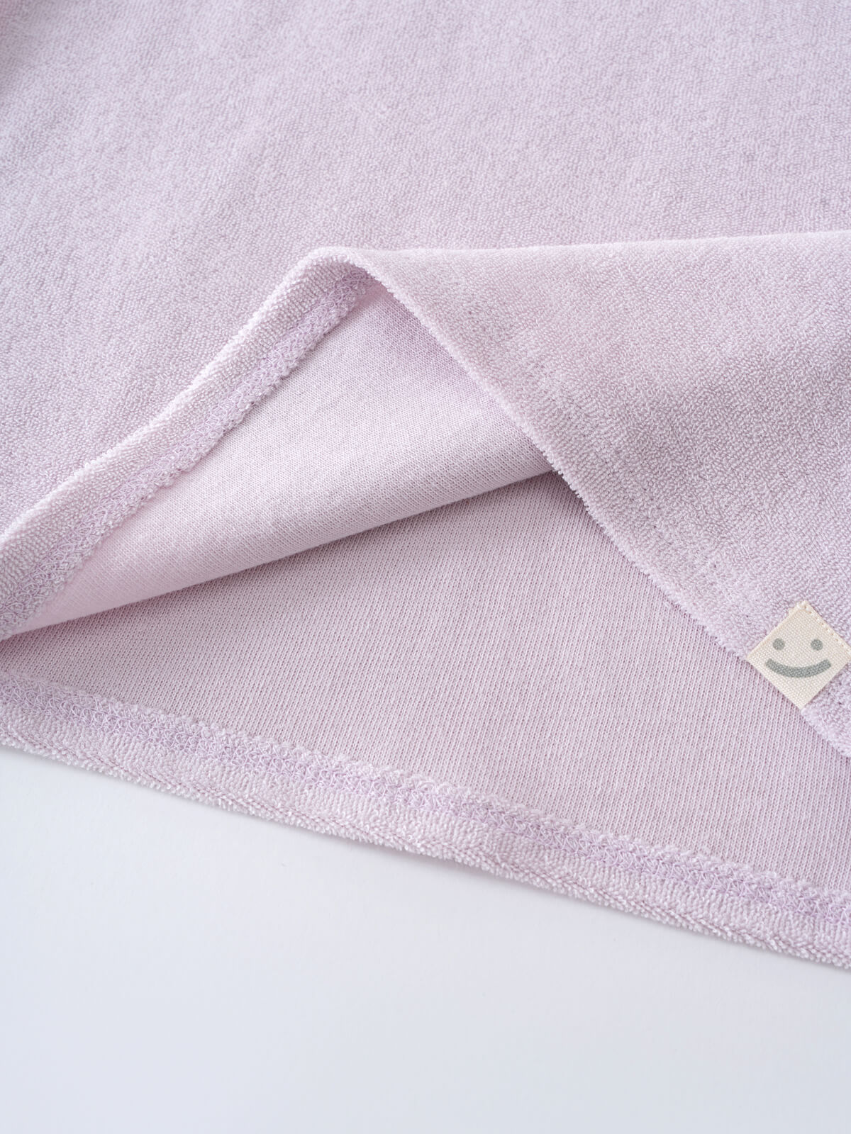 Close-up of a light purple towelling fabric with folded corner and tag Lara Towelling Tee Shirt - Lilac Girls