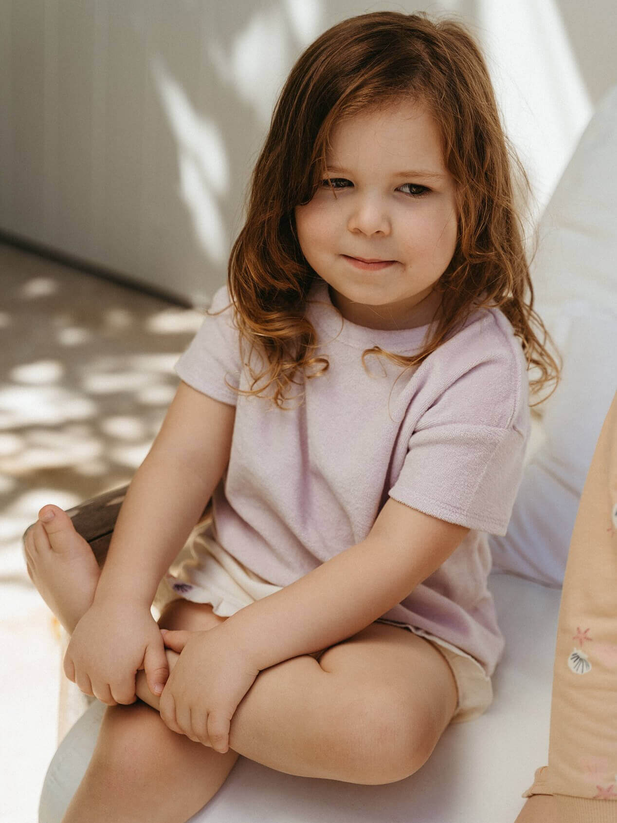 Young child sitting on a white surface with a neutral background