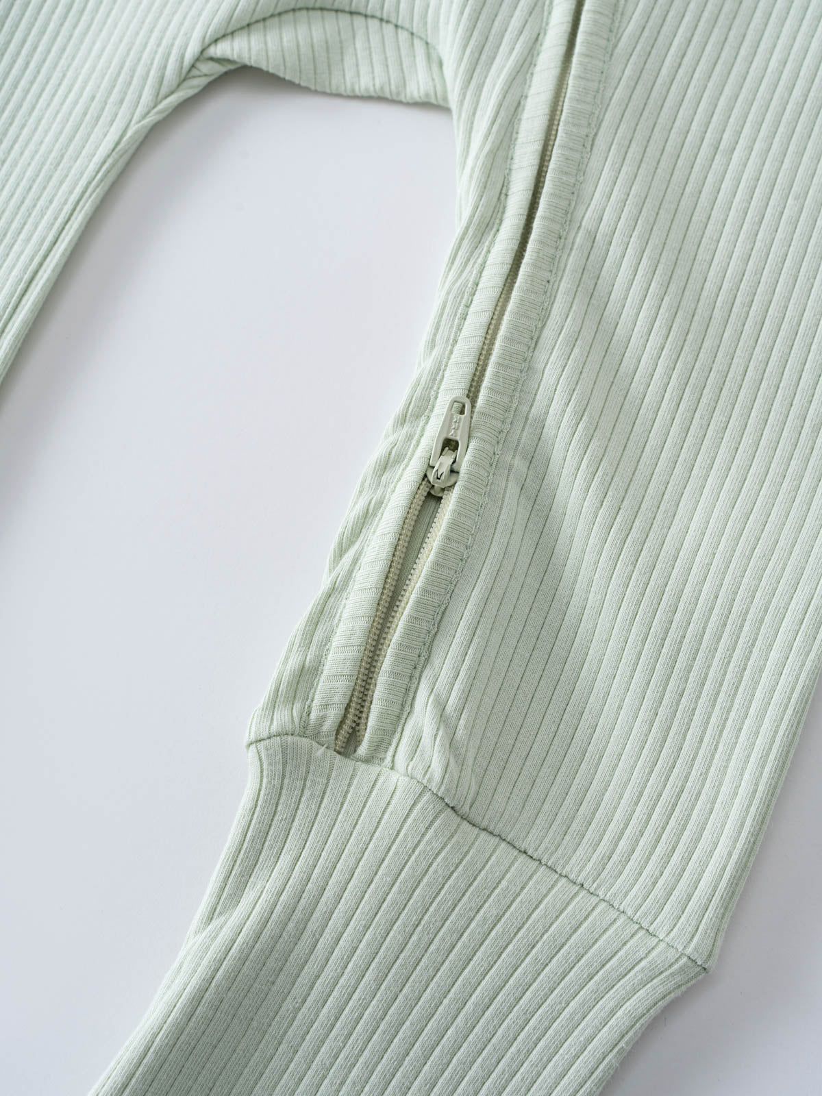 Close-up of a pale green ribbed fabric garment with zipper detail Levi Long Sleeve One Piece - Matcha Baby boy