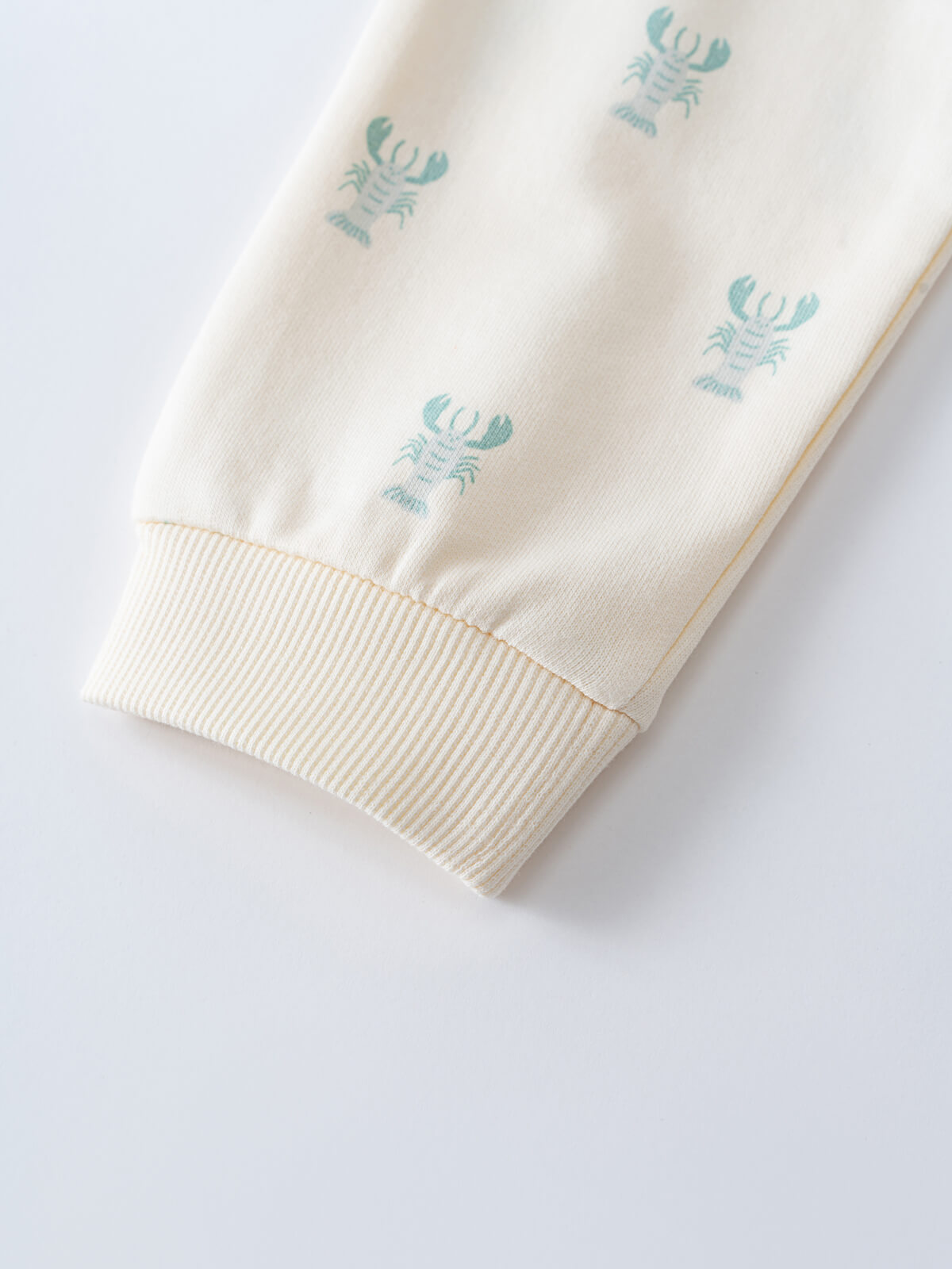 Close-up of cream fabric pant leg with teal lobster print and ribbed cuff Liam Sweatpants - Charlie's Friends Baby boy