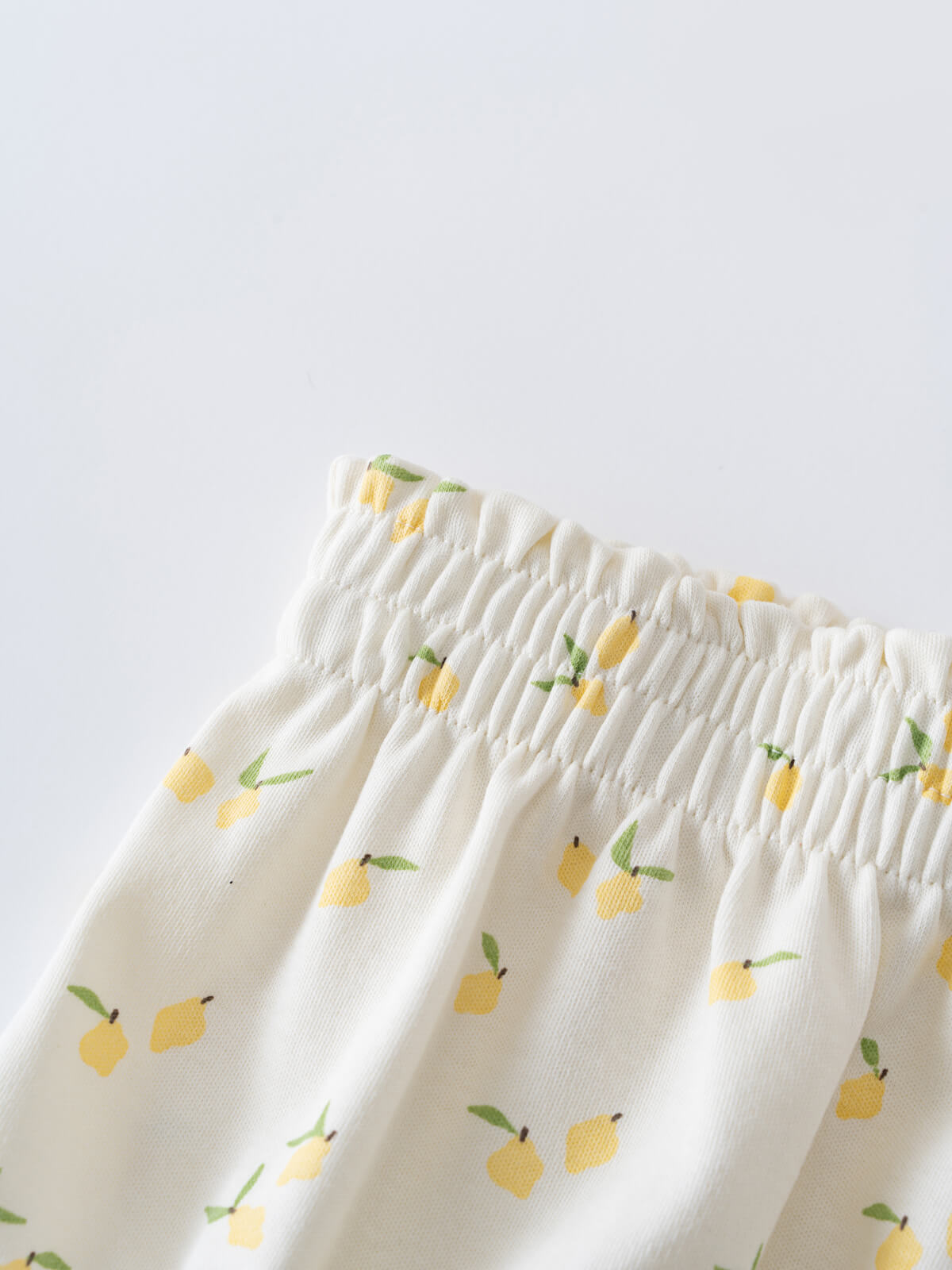 Close-up of white fabric waistband with yellow lemon and green leaf pattern Mabel Bloomers - Lemons Baby girl