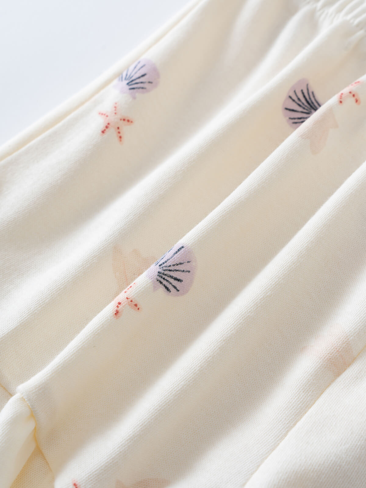 Close-up of cream fabric with small embroidered shell designs Madison Shorts - Beach Shells Girls