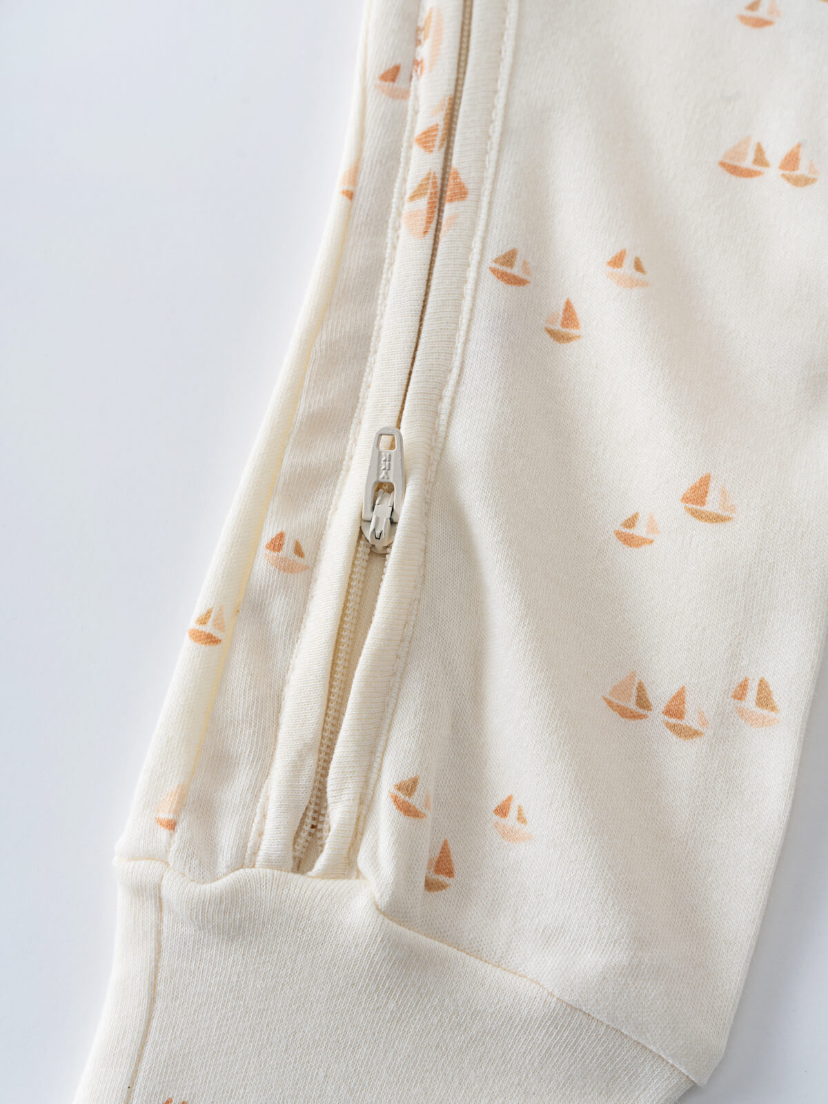 Close-up of cream fabric with orange sailboat print and zipper detail Miles Long Sleeve One Piece - Sailing Baby boy