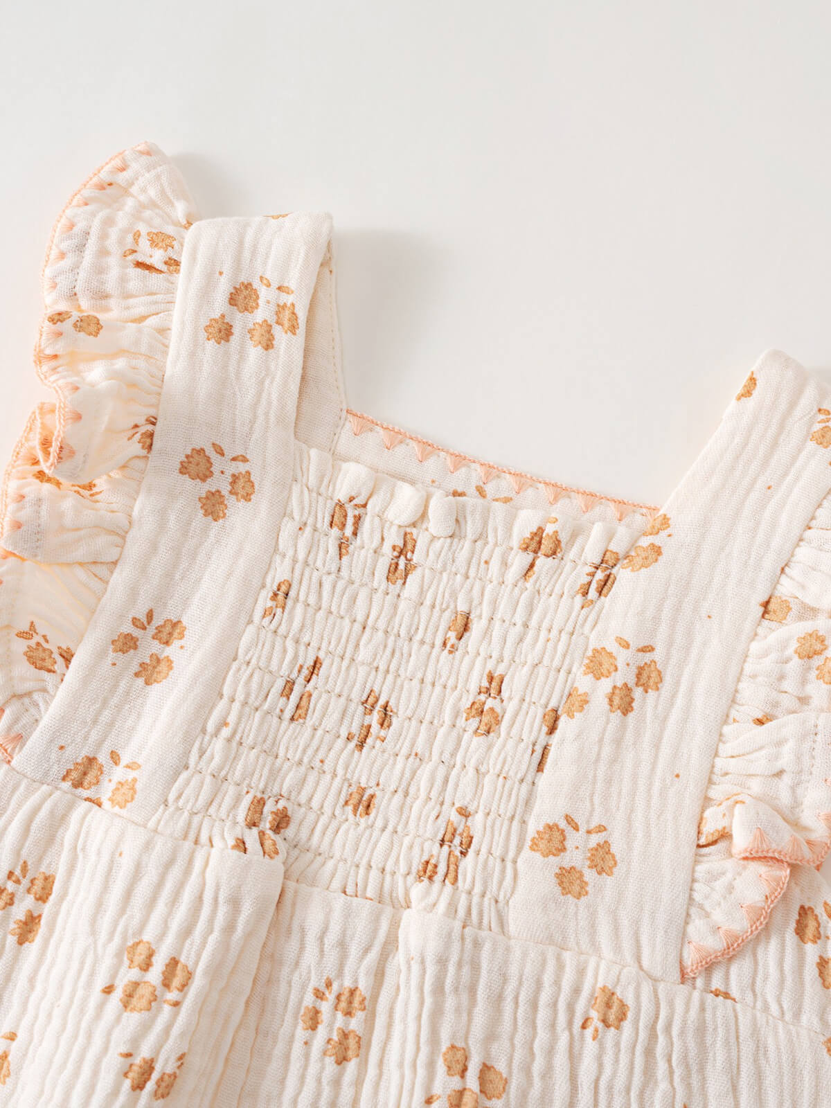 Close-up of white smocked baby romper with orange floral print and ruffled straps Piper Romper - Petal Paws Baby girl