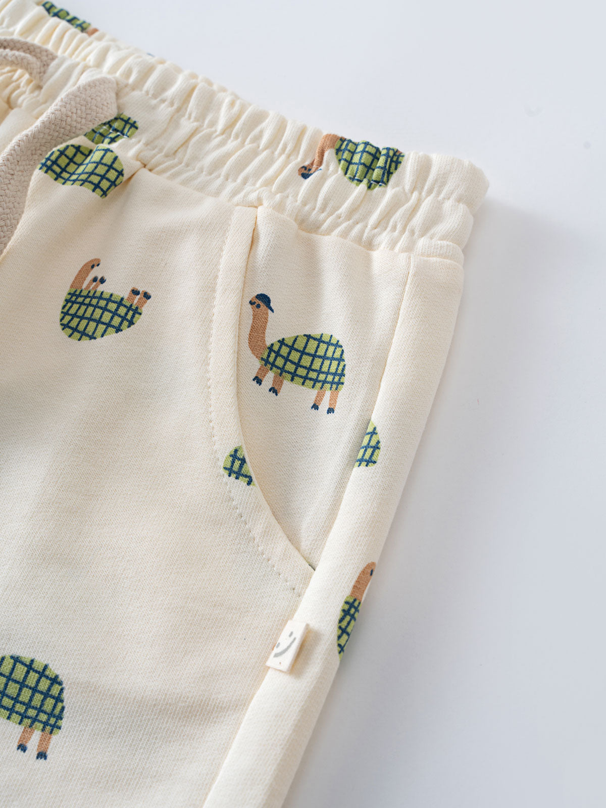Close-up of cream-colored shorts with turtle pattern and elastic waistband Remi Shorts - Tortie Boys