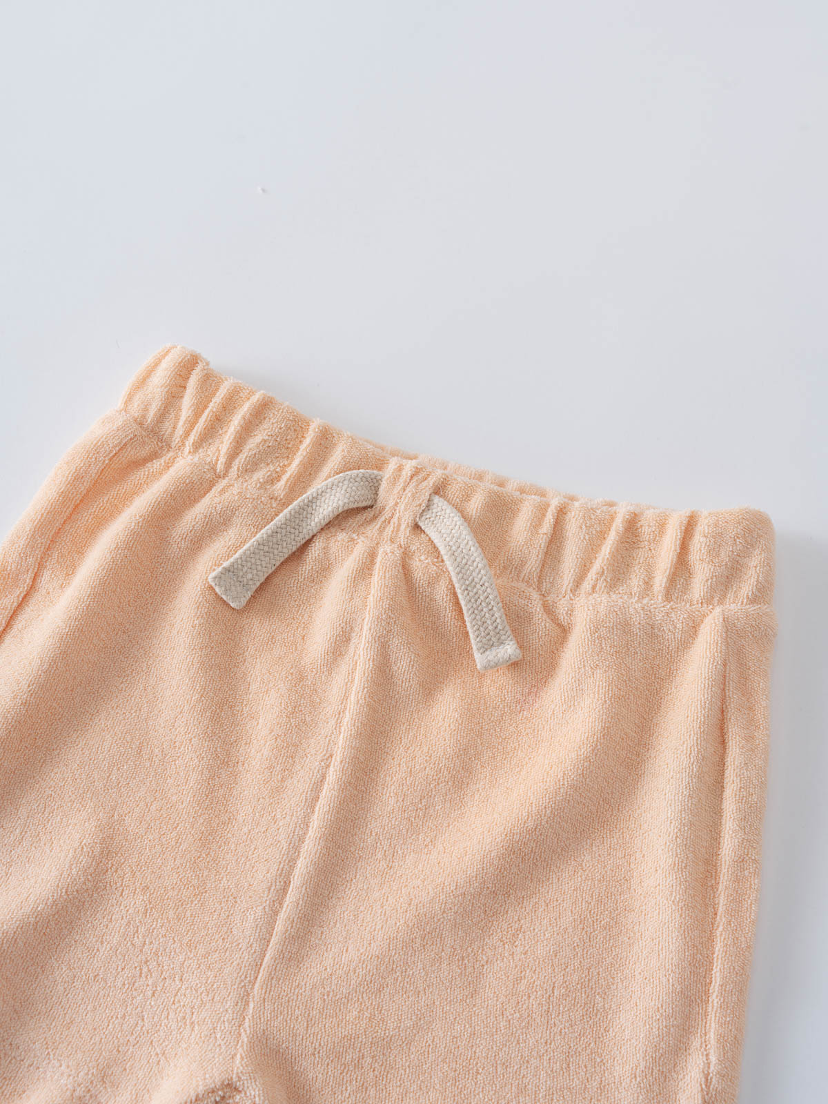 Close-up of peach towelling shorts with elastic waistband and cream drawstring Riley Towelling Shorts - Apricot Baby girl