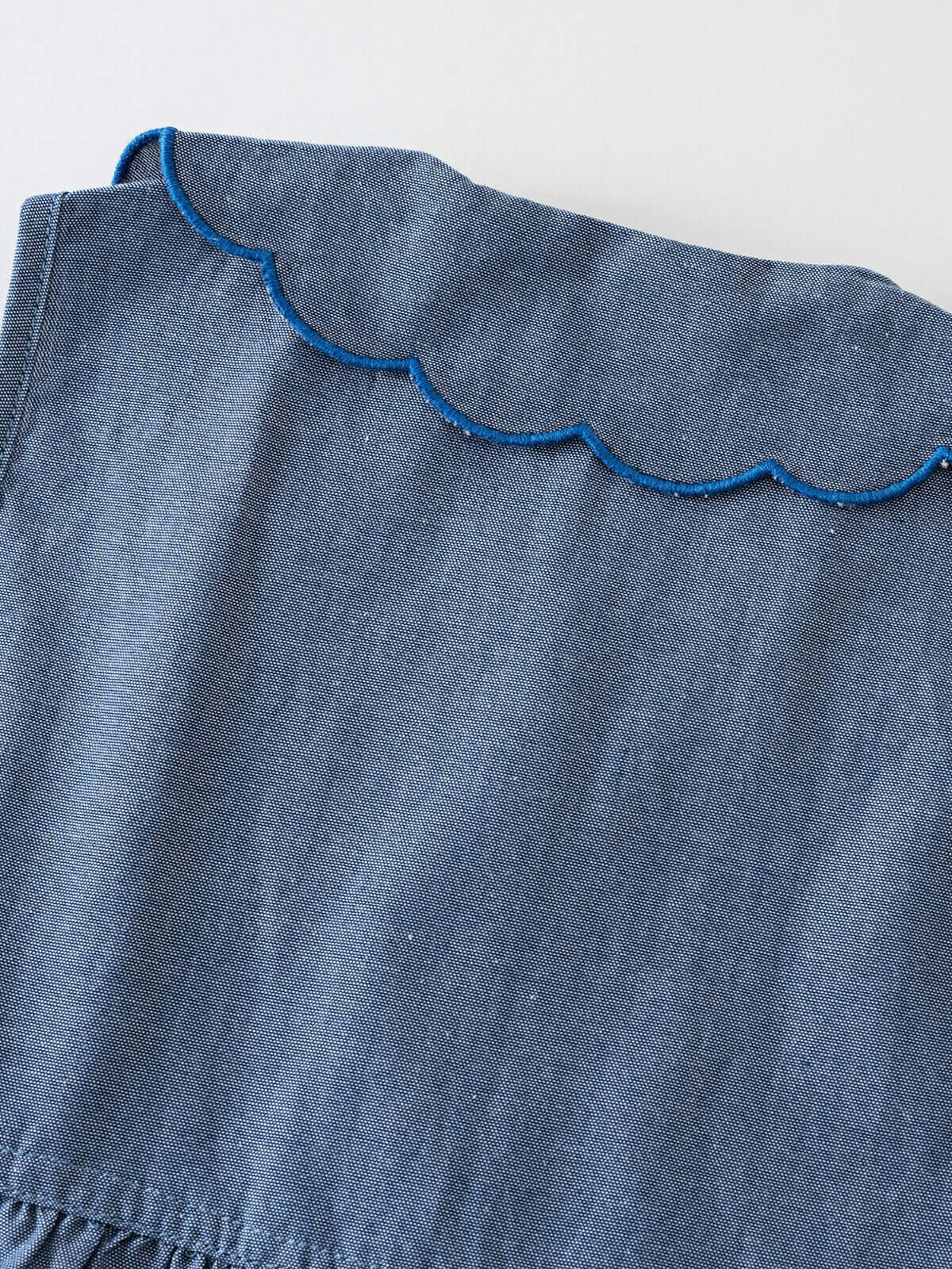 Close-up of blue chambray fabric with scalloped blue trim detail Skylar Dress - Blue Chambray Girls