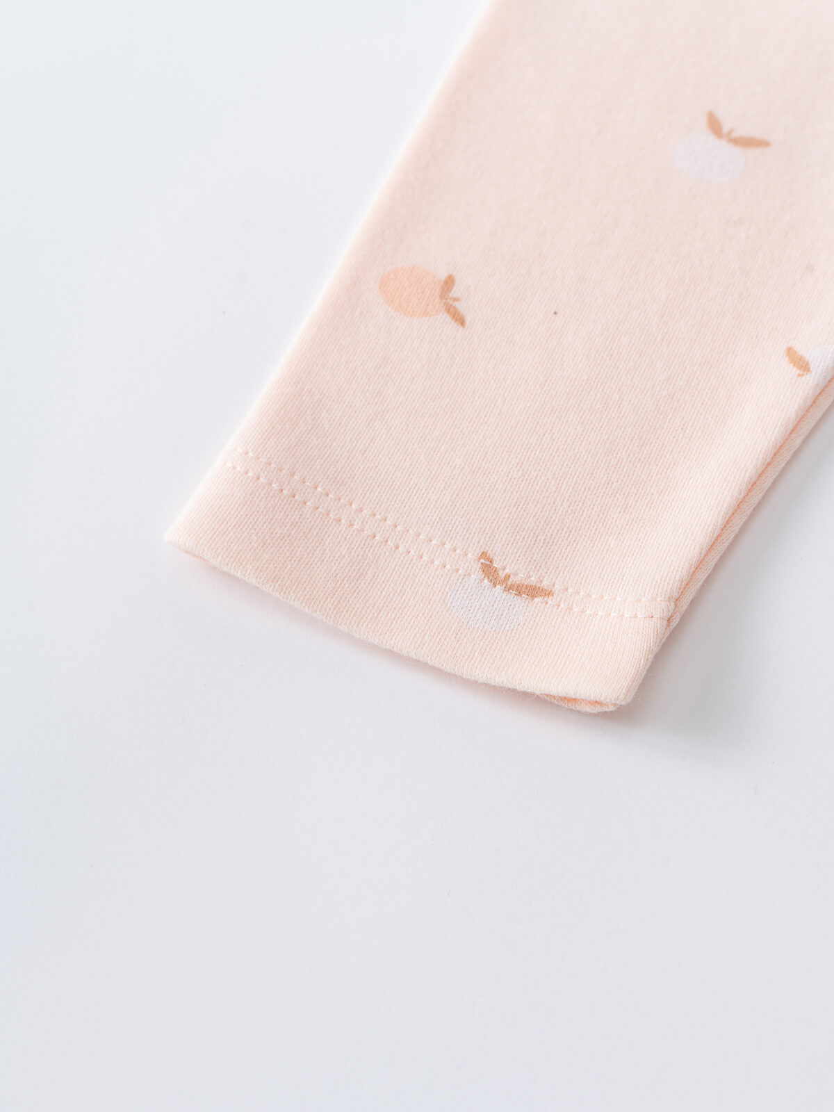 Close-up of pale pink fabric with small peach apple print pattern Stella Leggings - Apples Baby girl