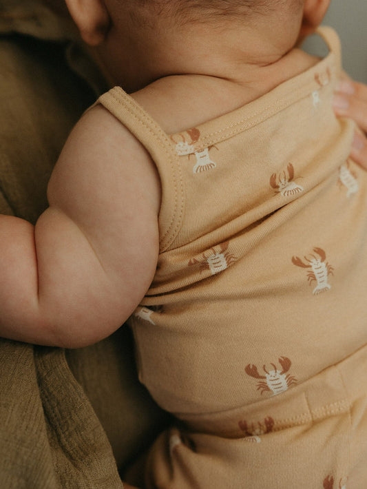 Newborn baby held against a parent, dressed in a soft cotton bodysuit