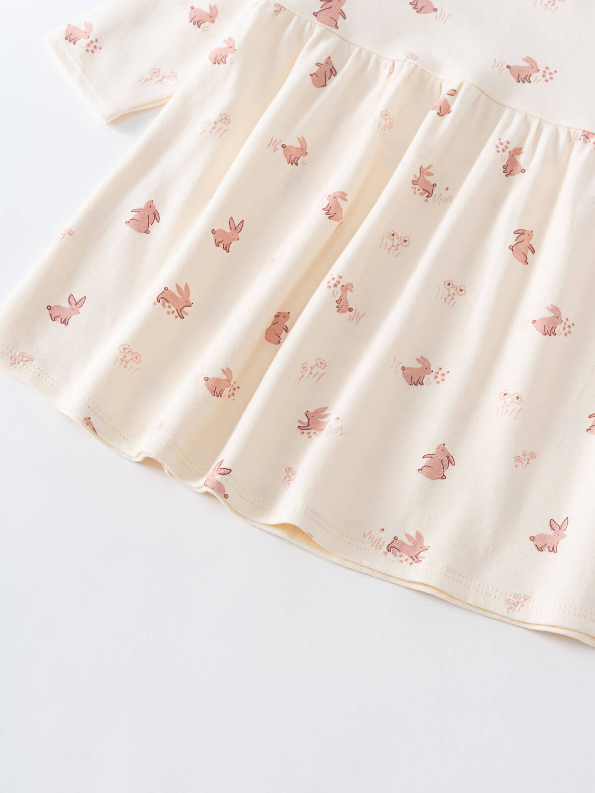 Close-up of cream-colored fabric with pink rabbit print pattern Baby Long Sleeve Jersey Dress - Meadow Friends Ecru Baby girl
