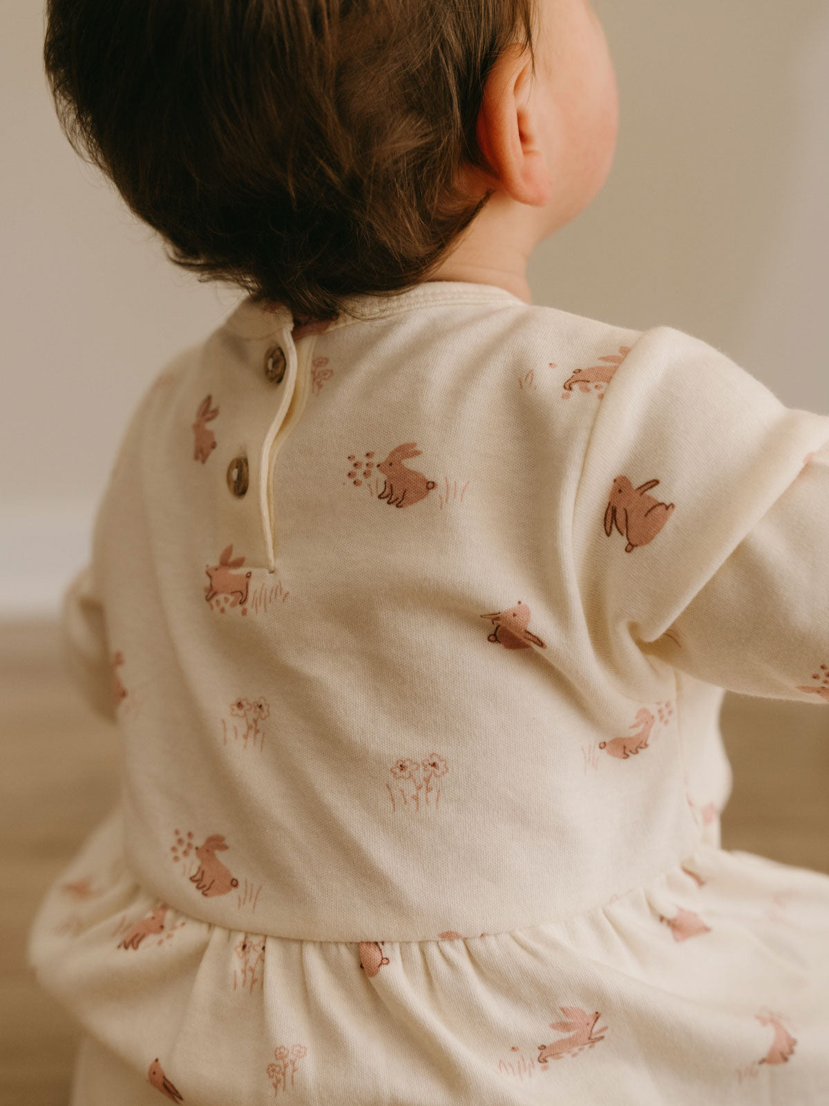 Child seen from behind wearing cream-colored dress with animal print pattern Baby Long Sleeve Jersey Dress - Meadow Friends Ecru Baby girl