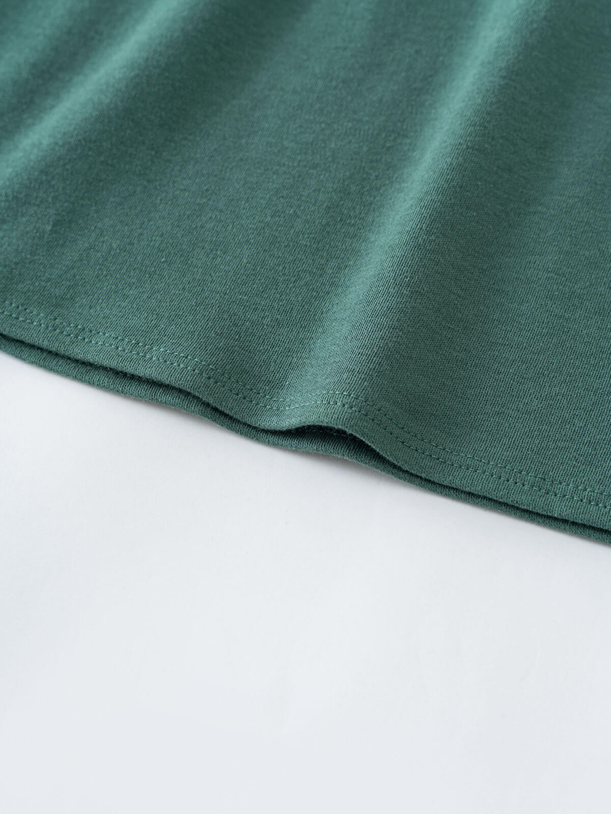 Close-up of teal green jersey fabric with hemmed edge Baby Long Sleeve Jersey Dress - Meadow Friends Baby girl