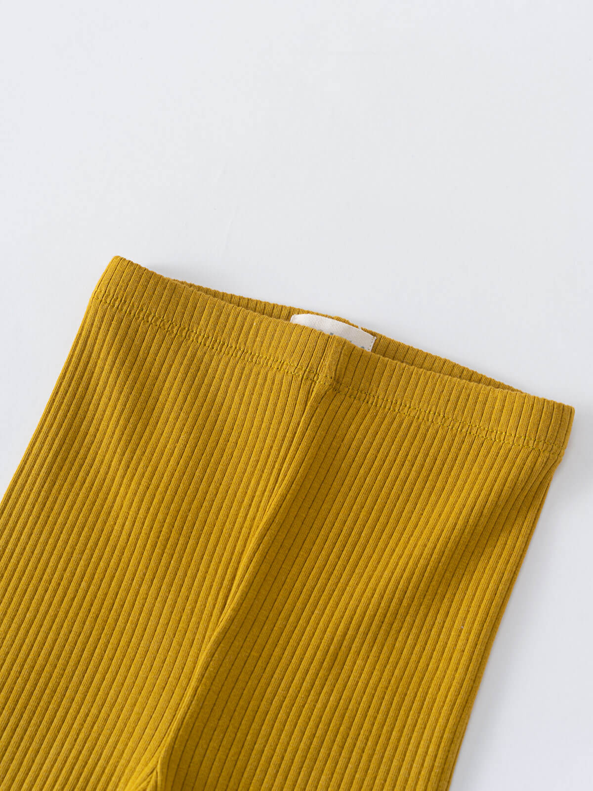 Close-up of mustard yellow ribbed fabric leggings with elastic waistband and white tag Baby Ribbed Leggings - Golden Pear Baby boy