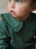 Baby wearing a dark green ruffle collar top looking upward Baby Ruffle Top - Balsam Baby girl