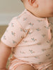 Baby wearing a pink floral printed short sleeve bodysuit with button detail Henley Short Sleeve Bodysuit - Wildflower Bouquet Pink Baby girl