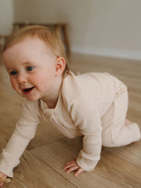 Baby crawling on wooden floor wearing cream ribbed long sleeve outfit Ribbed Long Sleeve One Piece - Clay Baby girl
