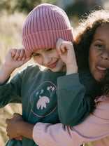 Child wearing pink ribbed beanie and green sweatshirt being held by adult Ribbed Beanie - Rosehip Girls
