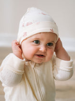 Baby wearing white hat with pink pattern and cream textured outfit Knot Hat - Meadow Friends Ecru Baby girl