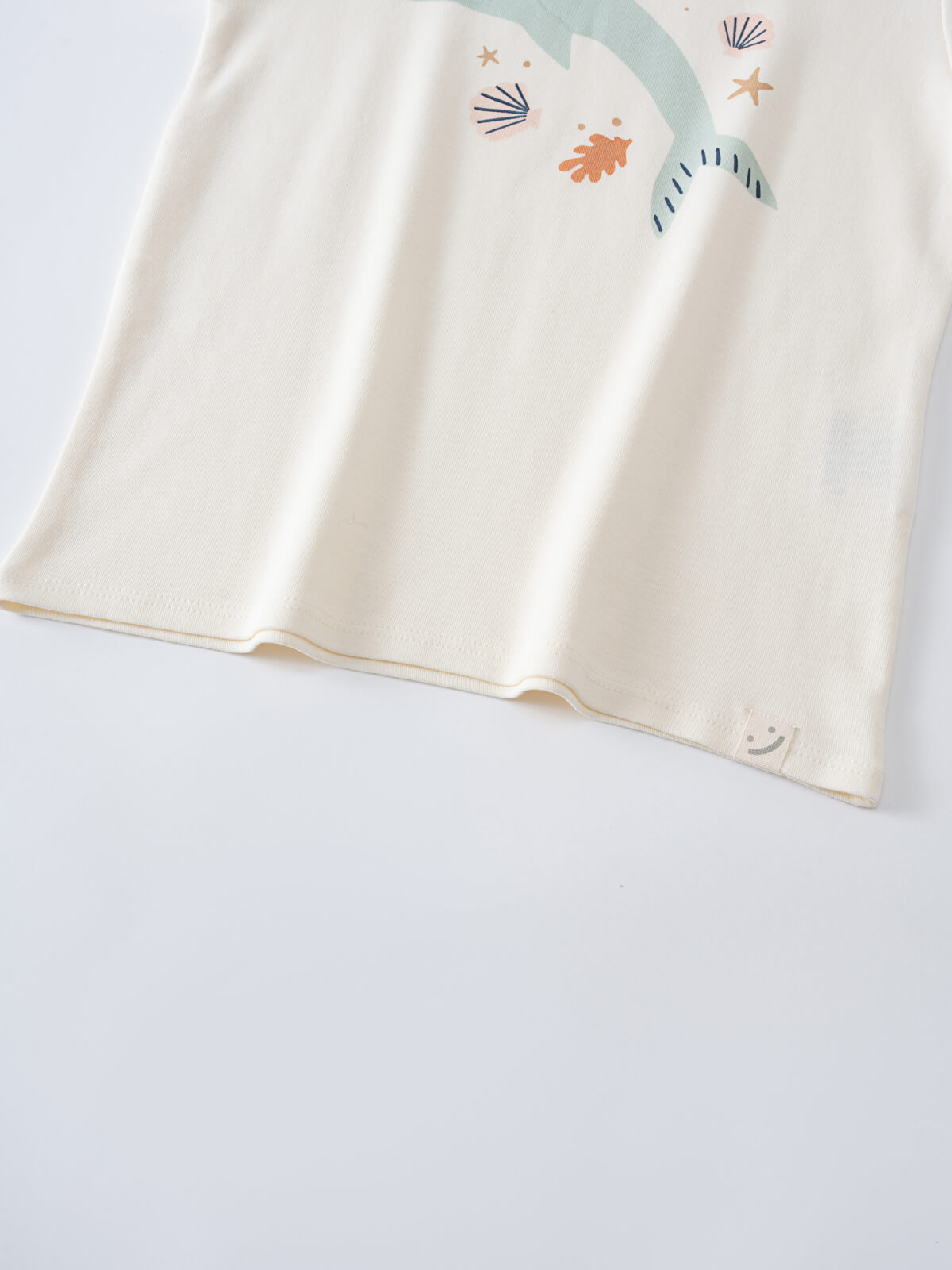 Close-up of cream-colored fabric with ocean-themed prints including shells and starfish Feature Print Short Sleeve Tee - Dolphin Short Sleeve Tee Shirt - Dolphin Girls