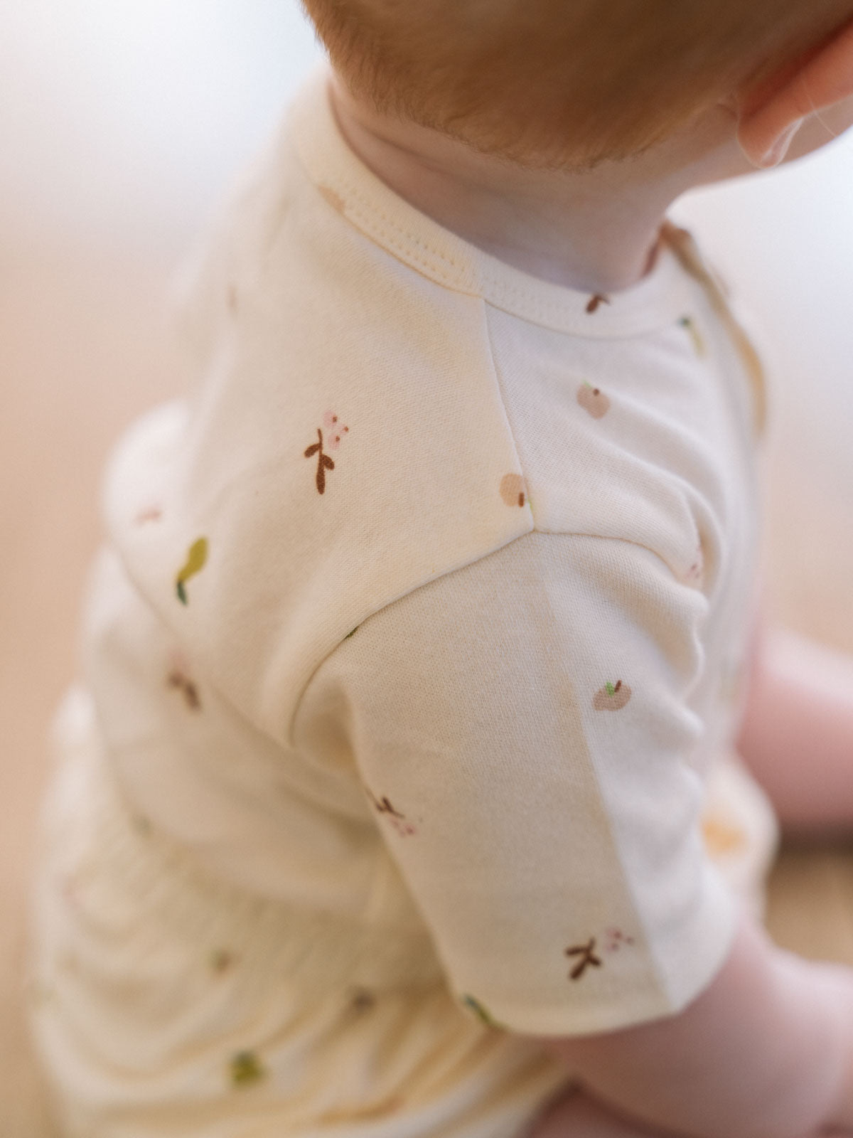 Close-up of baby wearing cream bodysuit with small embroidered botanical pattern Henley Short Sleeve Bodysuit - Autumn Harvest Ecru Baby girl