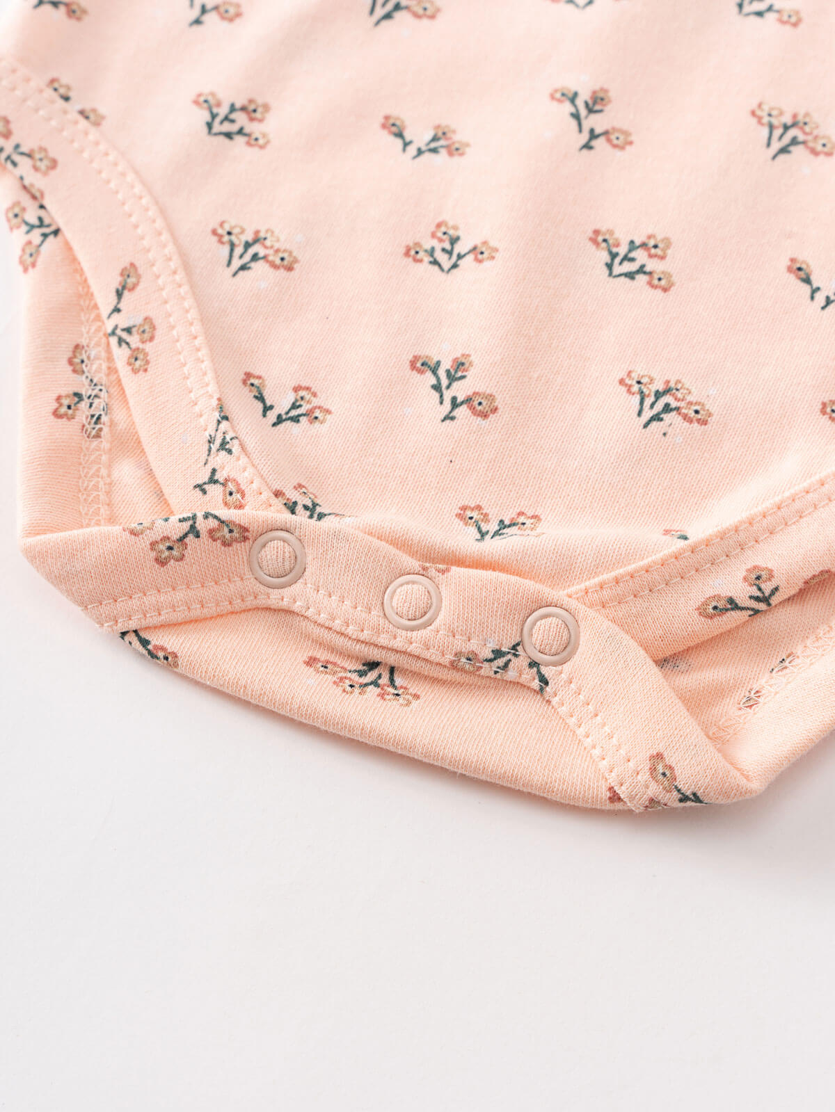 Close-up of pink floral patterned fabric with snap button closure detail Henley Short Sleeve Bodysuit - Wildflower Bouquet Pink Baby girl