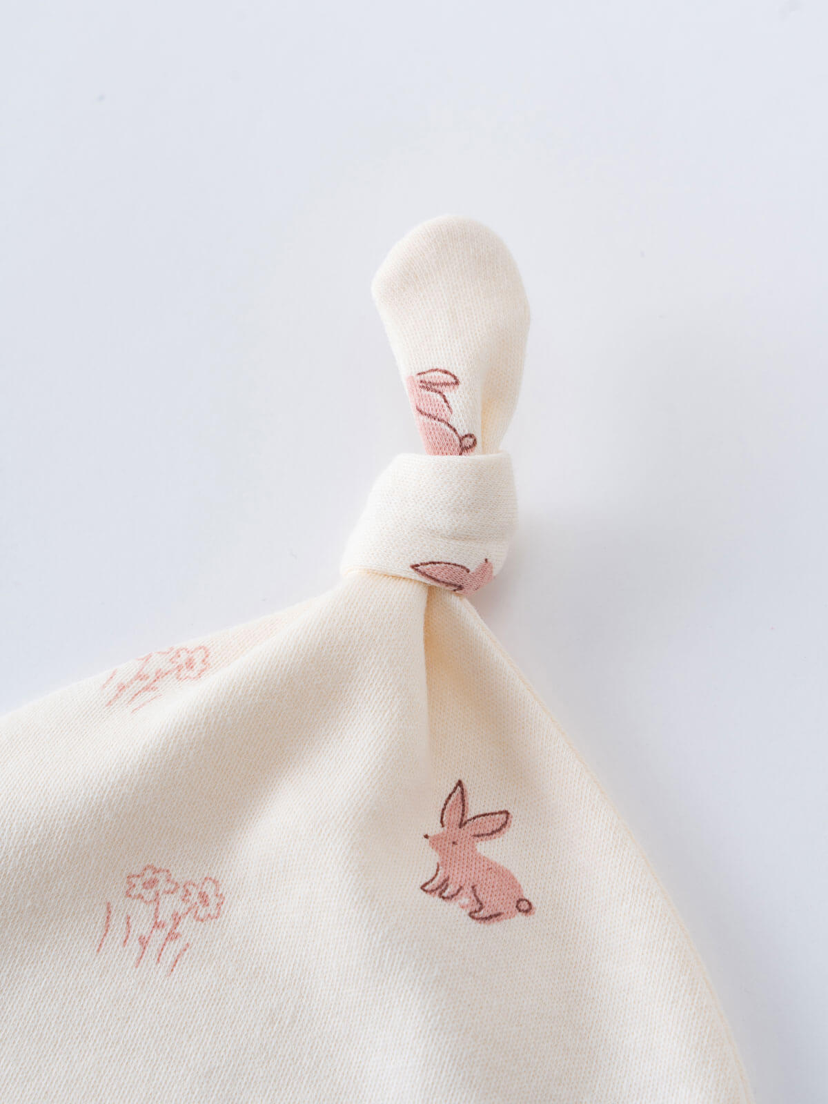 Cream colored fabric with pink embroidered bunnies and flowers tied in knot Knot Hat - Meadow Friends Ecru Baby girl