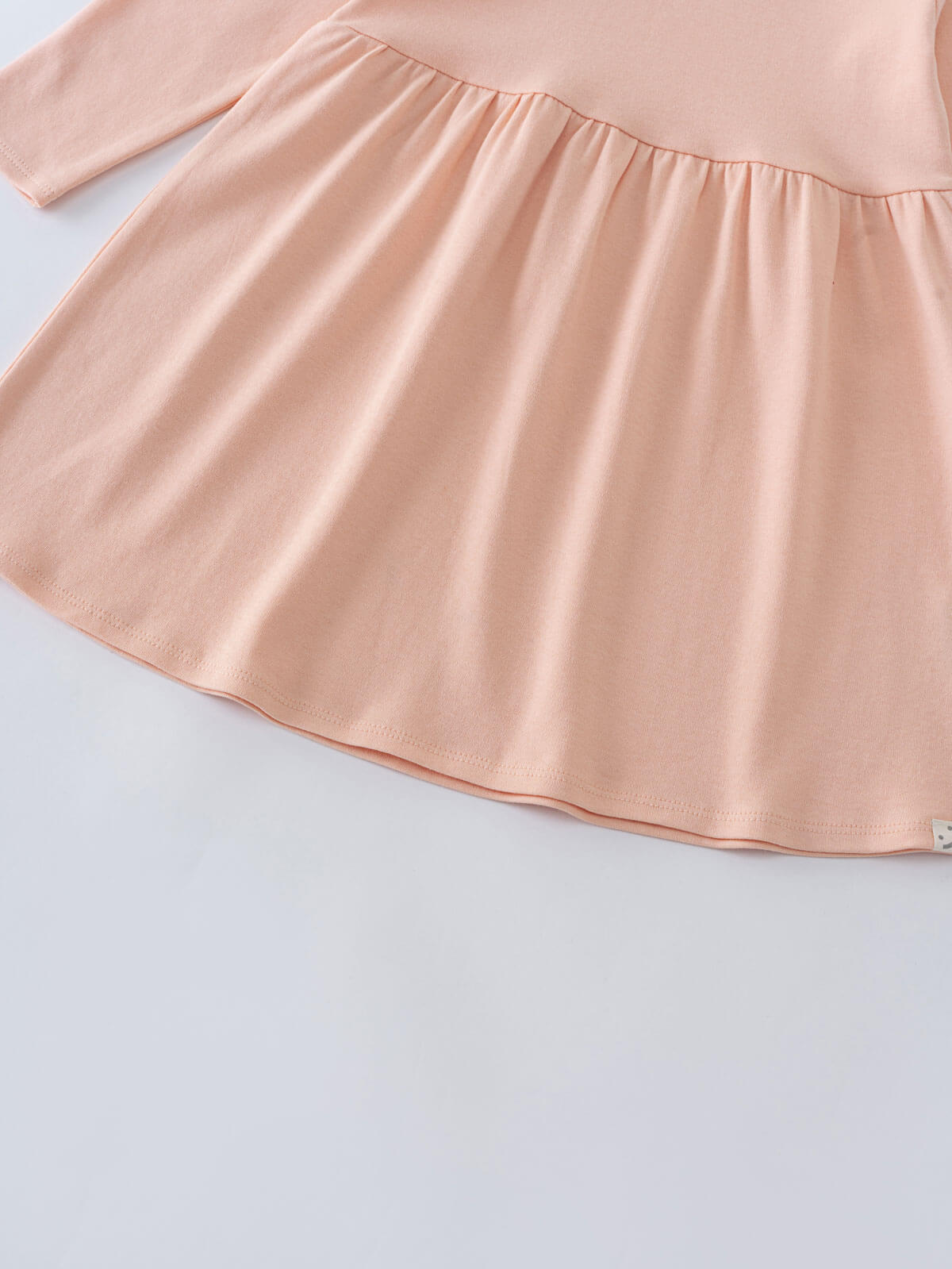Close-up of a pale pink gathered skirt portion of a dress Long Sleeve Jersey Dress - Mallow Girls