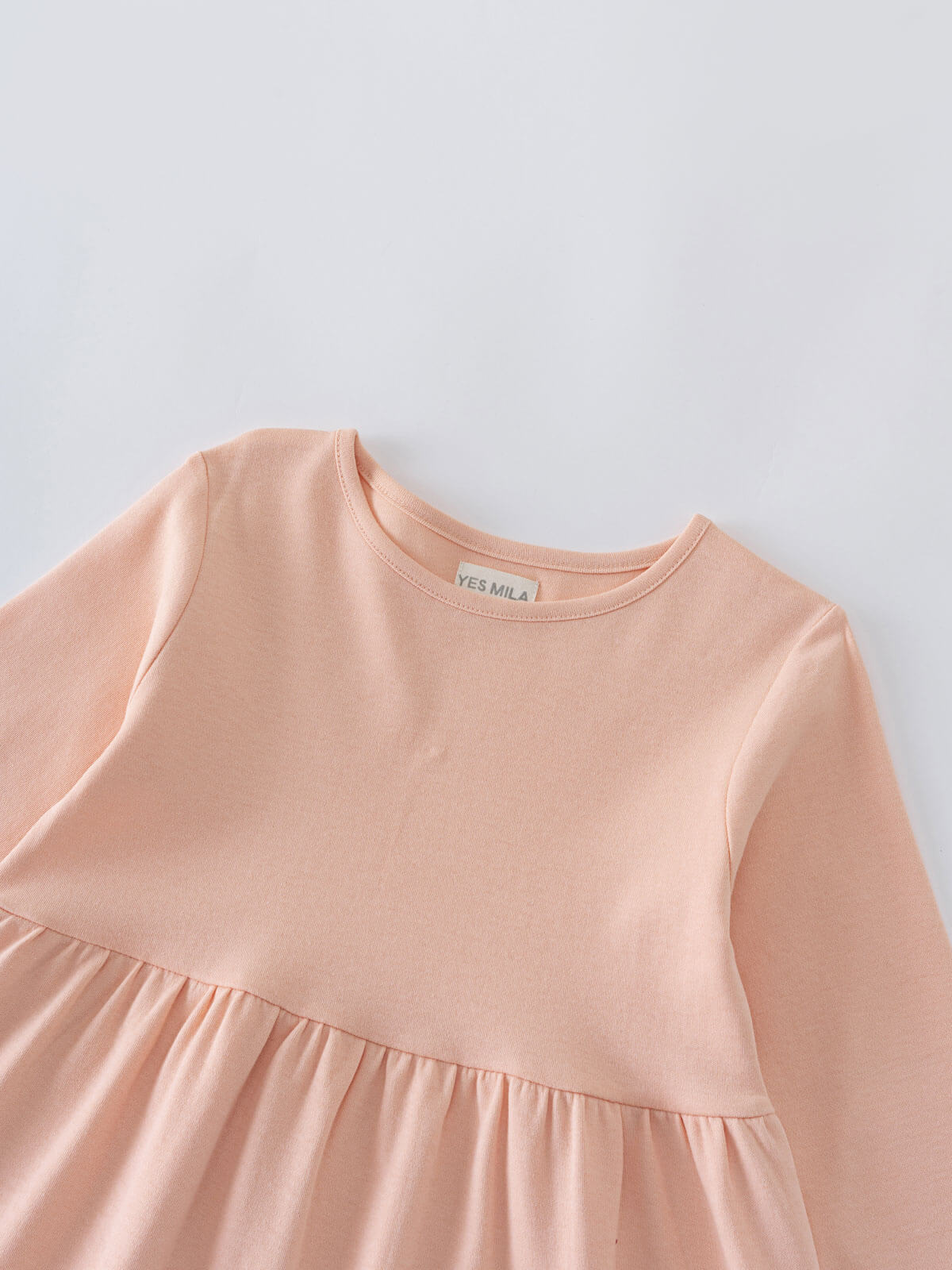 Close-up of a peach-colored dress with gathered waist detail Long Sleeve Jersey Dress - Mallow Girls