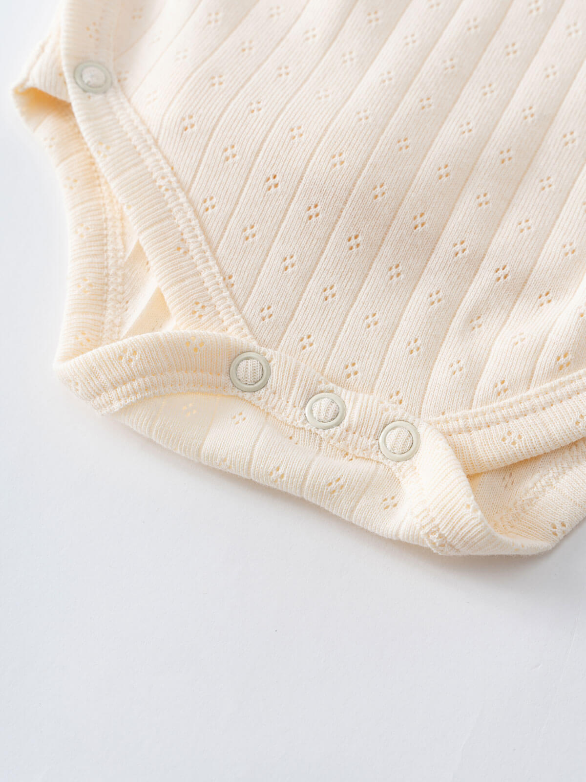 Close-up of cream-colored ribbed baby bodysuit with snap buttons and pointelle detail Pointelle Crossover Bodysuit - Ecru Baby boy