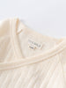 Close-up of cream-colored pointelle fabric bodysuit showing size label and neckline detail Pointelle Crossover Bodysuit - Ecru Baby boy