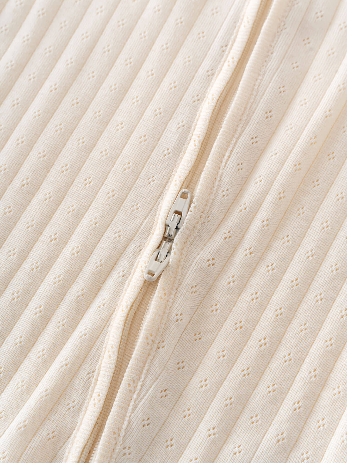 Close-up of a textured fabric with a zipper on a beige background Pointelle Long Sleeve One Piece - Ecru Baby boy