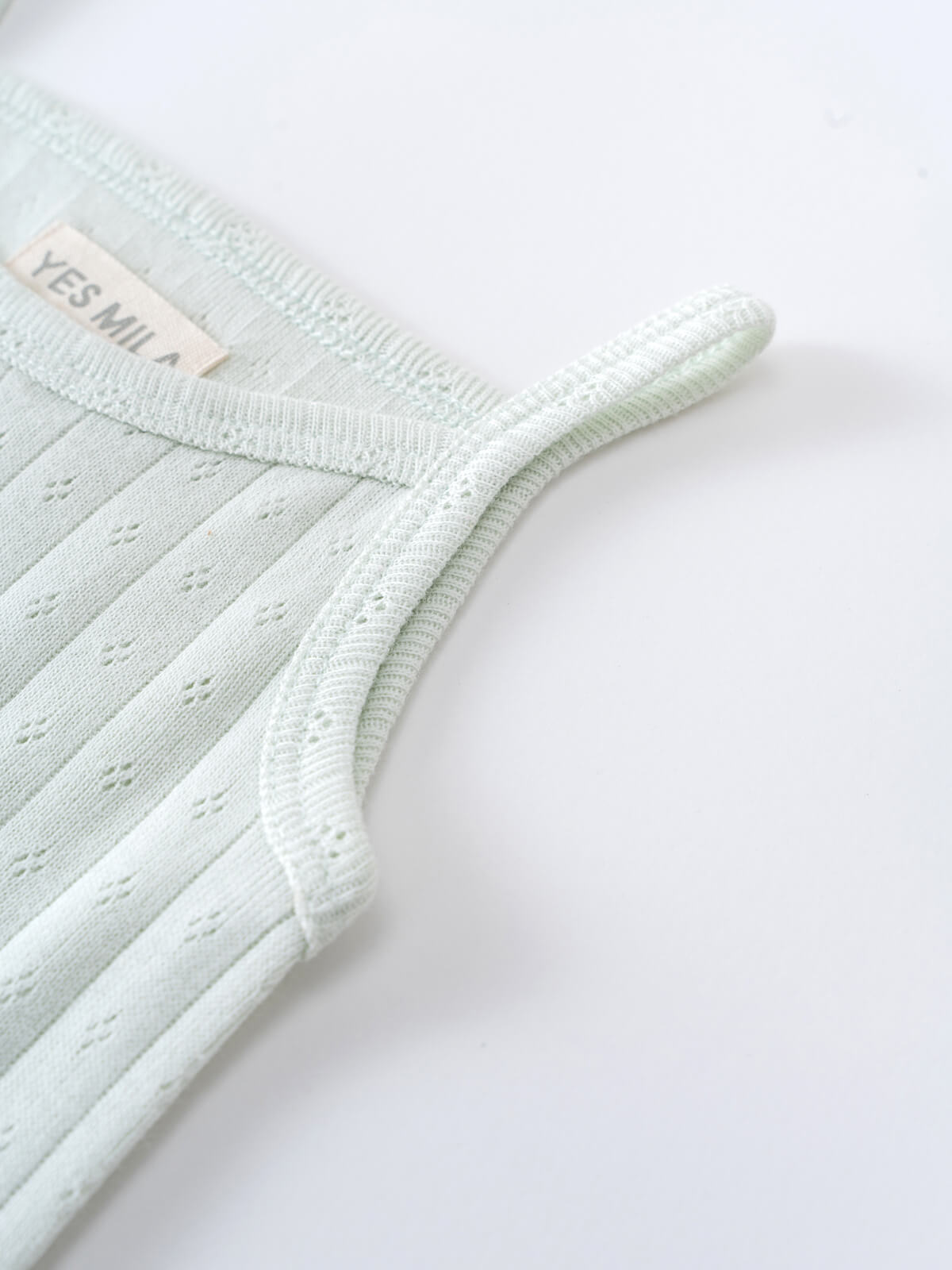 Close-up of a light green ribbed knit bodysuit with label Pointelle Singlet Bodysuit - Sea Foam Baby boy
