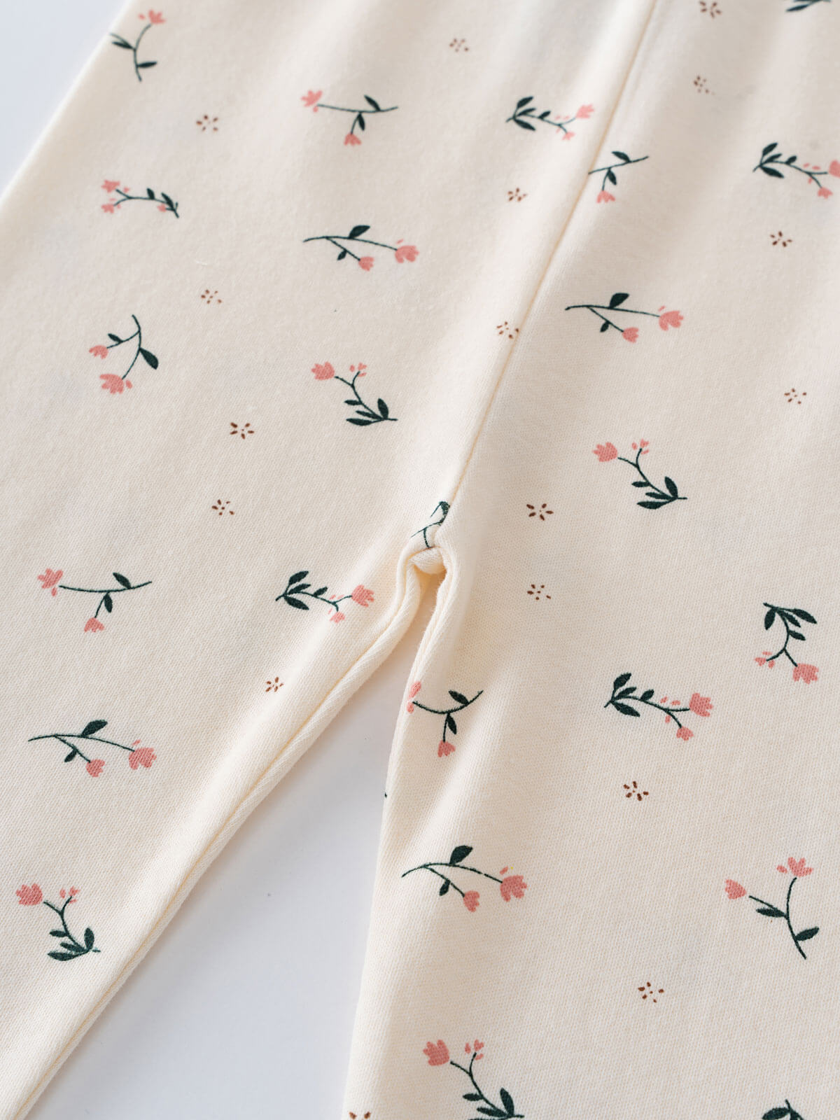 Close-up of cream fabric with pink flowers and dark green leaves pattern Printed Leggings - Wild Meadow Ecru Girls