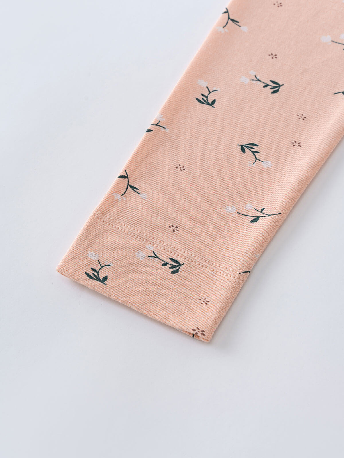 Peach fabric with small floral and plant print pattern laid flat Printed Leggings - Wild Meadow Mallow Girls