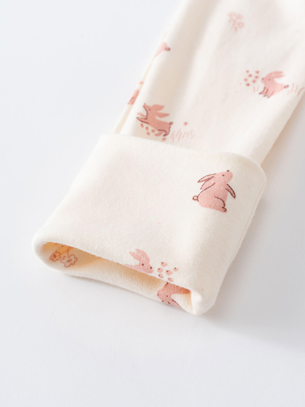 White fabric with pink rabbit pattern, folded cuff showing yellow interior Printed Long Sleeve One Piece - Meadow Friends Ecru Baby girl