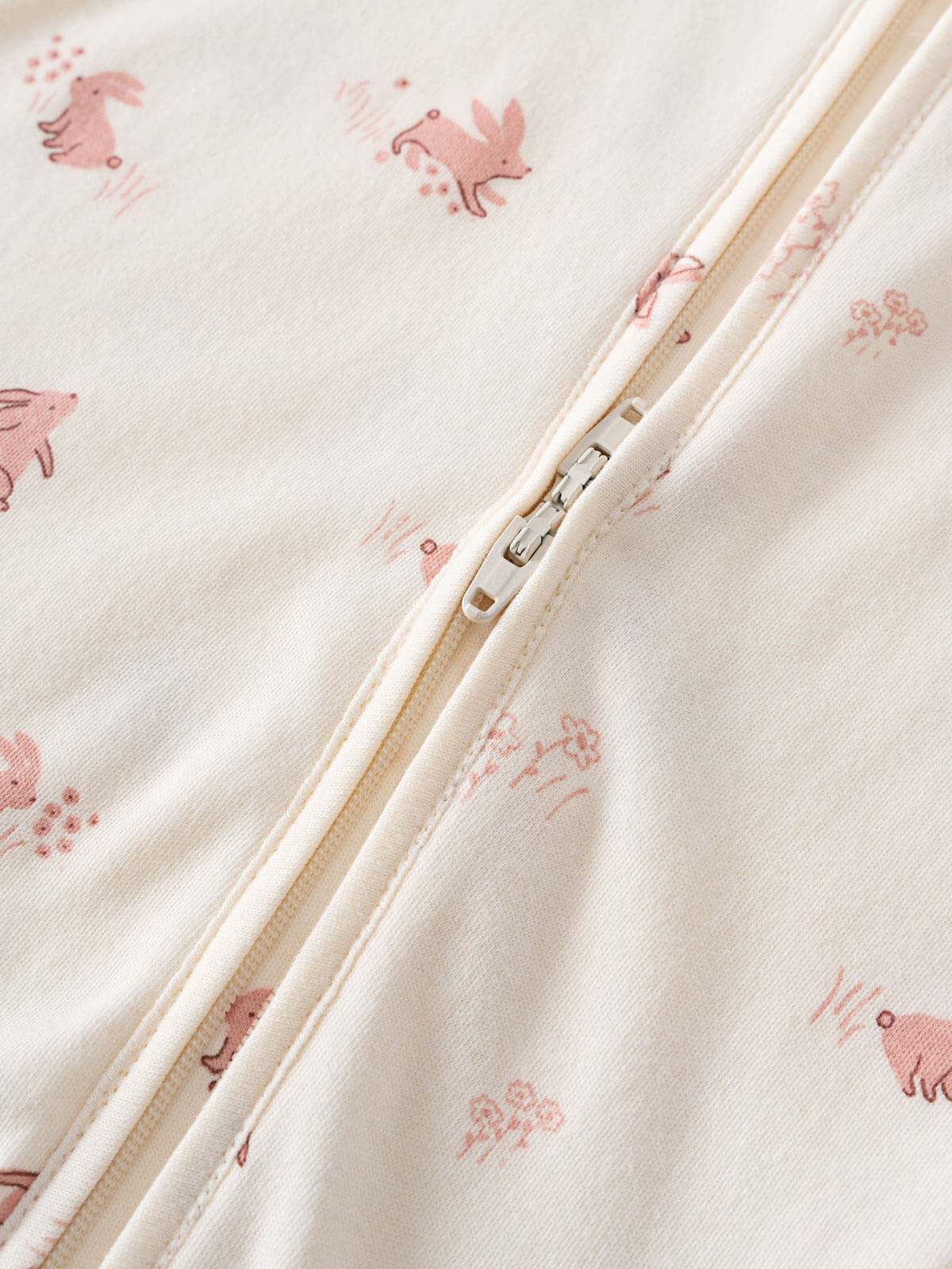 Close-up of cream fabric with pink animal print and beige zipper detail Printed Long Sleeve One Piece - Meadow Friends Ecru Baby girl
