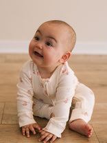 Baby sitting on wooden floor wearing white printed long sleeve one piece Printed Long Sleeve One Piece - Meadow Friends Ecru Baby girl