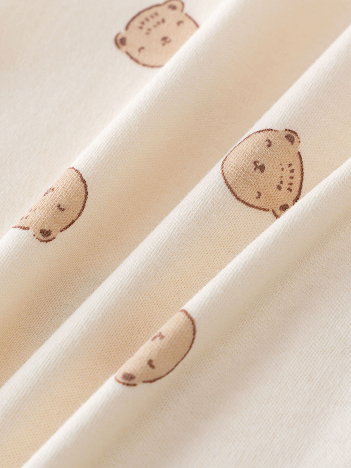 Close-up of cream fabric with small brown bear face prints Printed Long Sleeve One Piece - Cosy Bear Ecru Baby boy