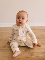 Baby sitting on wooden floor wearing cream pajamas with bear print Printed Long Sleeve One Piece - Cosy Bear Ecru Baby boy