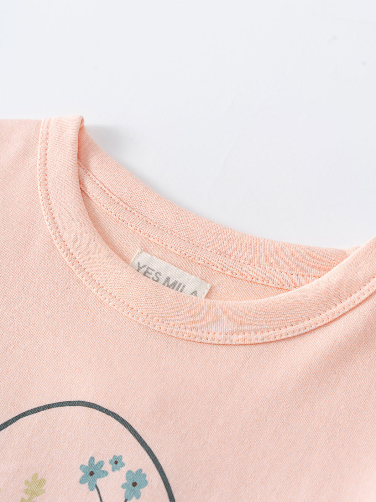Close-up of a peach t-shirt neckline with floral design detail Printed Long Sleeve Tee - Dove Girls