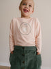 Young girl wearing a pink graphic tee and green corduroy skirt Printed Long Sleeve Tee - Dove Girls