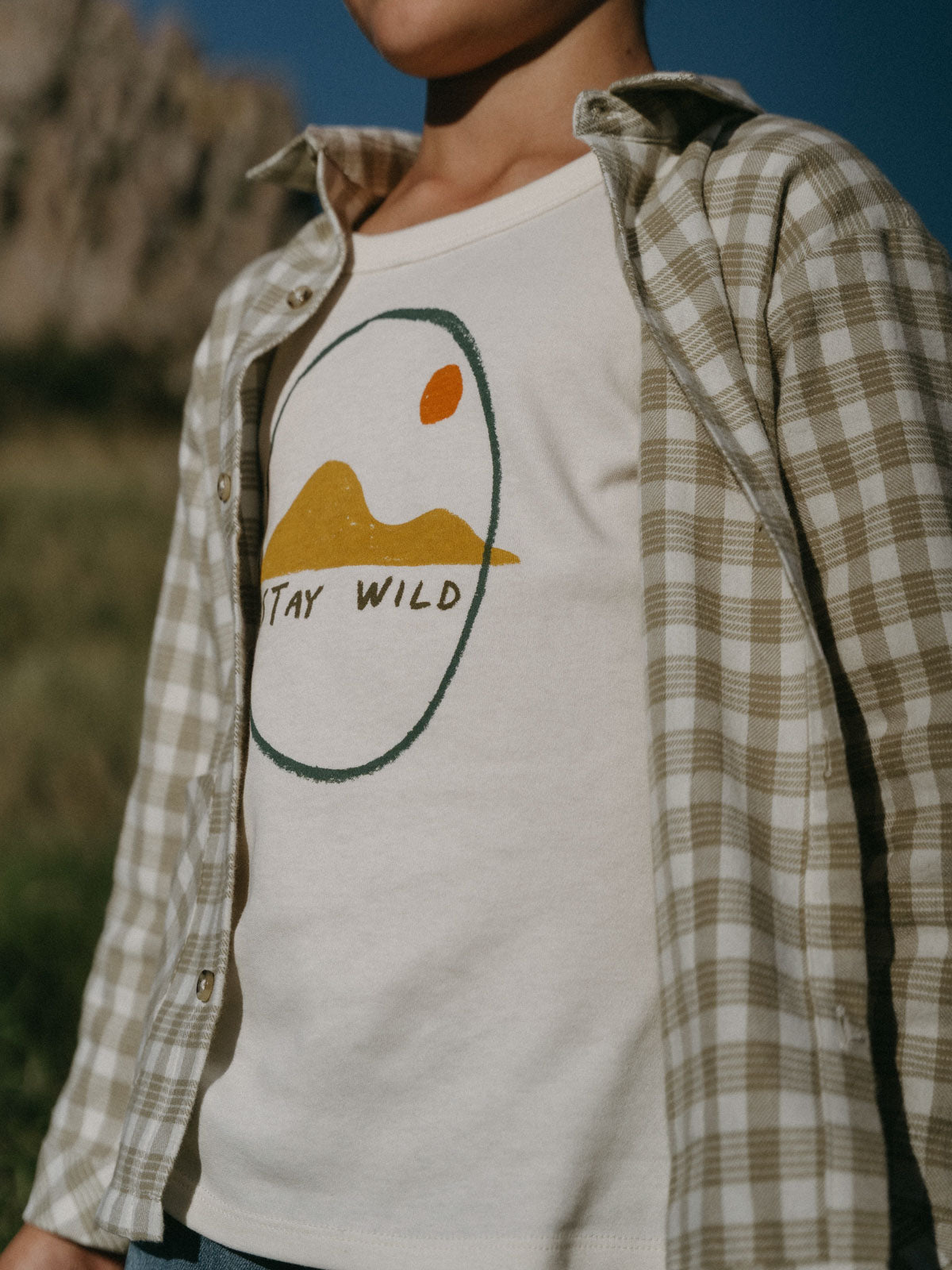 Boy wearing a white graphic tee and plaid shirt outdoors Printed Long Sleeve Tee - Stay Wild Boys